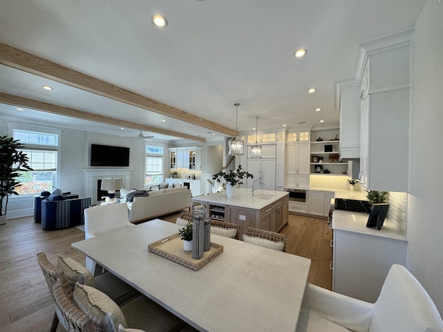 dining room with beamed ceiling, dark hardwood / wood-style floors, sink, and ceiling fan with notable chandelier