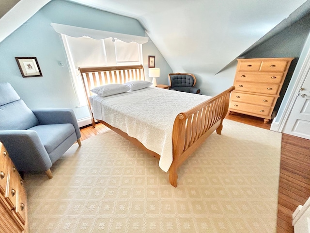 bedroom featuring light wood-type flooring and vaulted ceiling