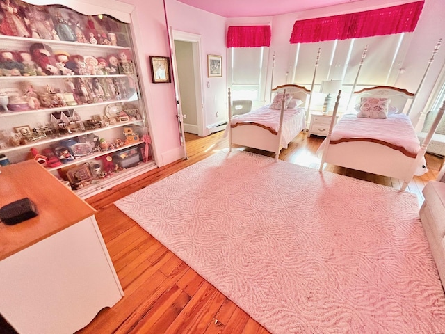 bedroom with a baseboard heating unit and hardwood / wood-style flooring