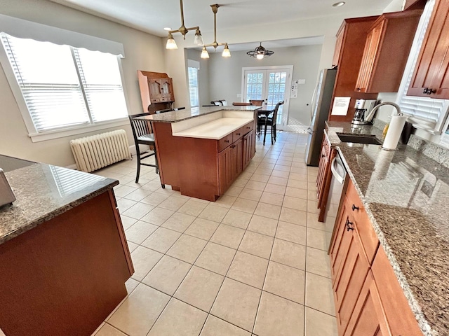 kitchen featuring a kitchen breakfast bar, light stone counters, decorative light fixtures, radiator heating unit, and a kitchen island