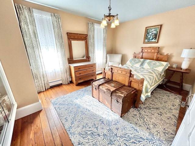 bedroom featuring light wood-type flooring, multiple windows, a baseboard radiator, and an inviting chandelier