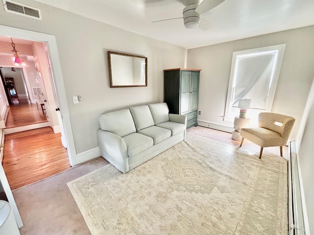 living room featuring light carpet, baseboard heating, and ceiling fan