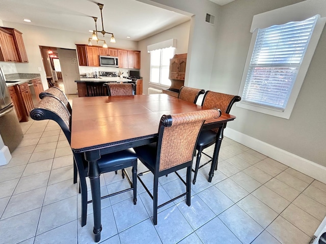 dining room featuring a wealth of natural light, light tile patterned floors, and a notable chandelier