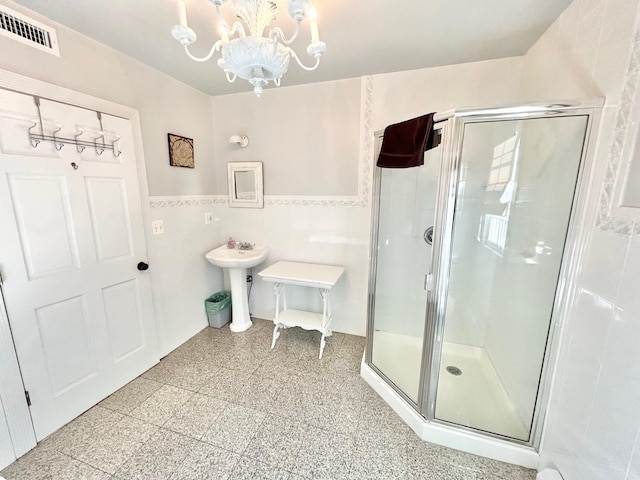 bathroom with a shower with door, tile walls, and a chandelier