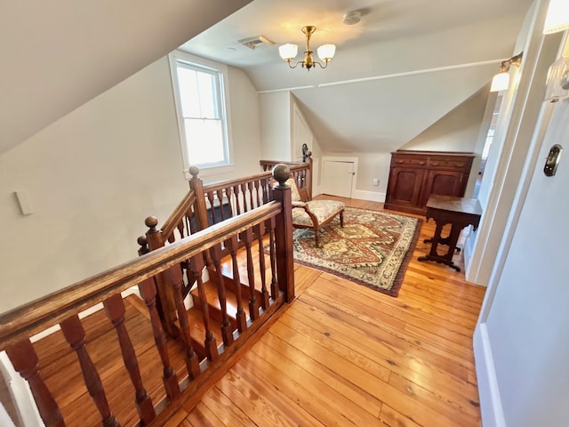 additional living space with a chandelier, vaulted ceiling, and light hardwood / wood-style floors