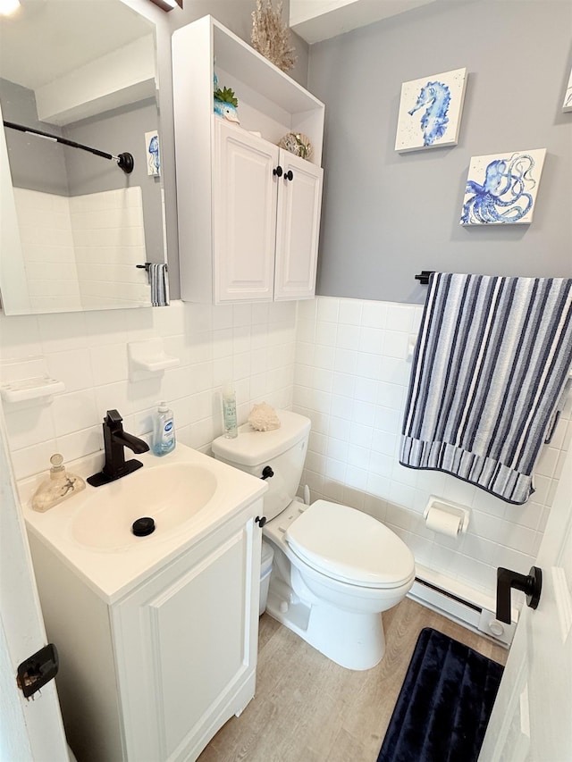 bathroom featuring toilet, wood-type flooring, tile walls, vanity, and a baseboard heating unit