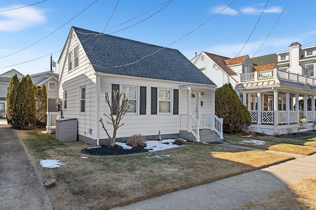 view of front of house with central AC, a balcony, and a front lawn