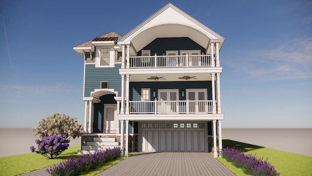 coastal home with decorative driveway, a balcony, and an attached garage