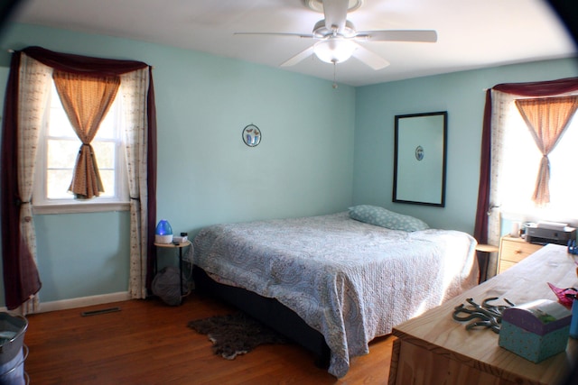 bedroom featuring ceiling fan, wood finished floors, visible vents, and baseboards