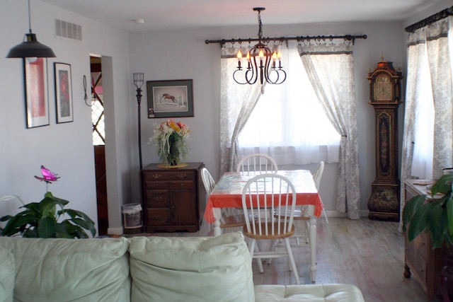 dining space featuring visible vents, a chandelier, and wood finished floors