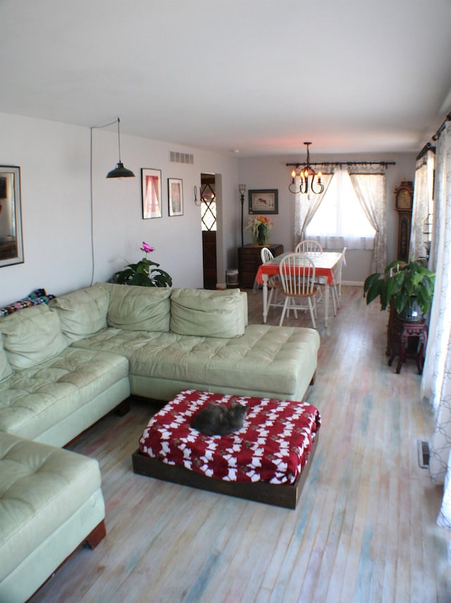 living room with a chandelier, visible vents, and wood finished floors