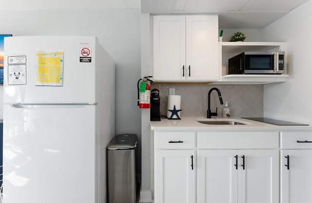 kitchen featuring white cabinets, white refrigerator, backsplash, and sink