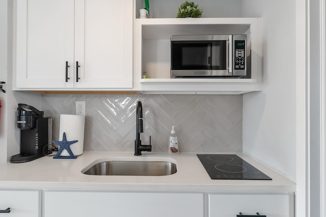 kitchen with decorative backsplash, sink, white cabinets, and black electric stovetop