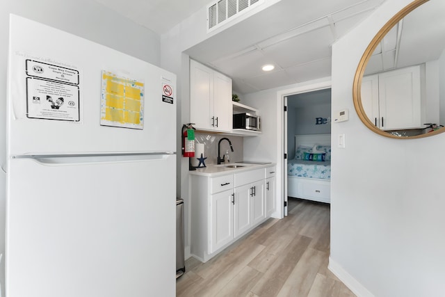 kitchen with white cabinetry, sink, white fridge, and light wood-type flooring