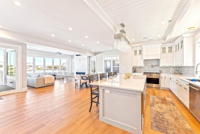 kitchen featuring white cabinets, a sink, stainless steel appliances, open floor plan, and a kitchen island