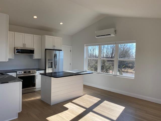 kitchen with stainless steel appliances, white cabinetry, dark wood-type flooring, and a wall mounted AC