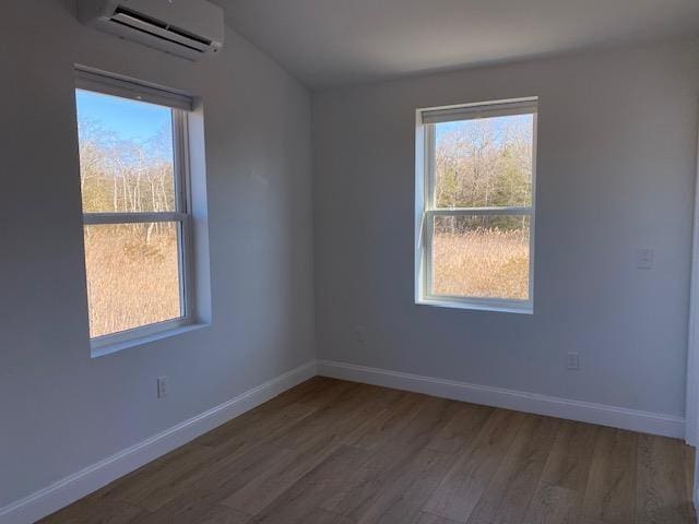 unfurnished room featuring hardwood / wood-style flooring, plenty of natural light, and a wall mounted AC