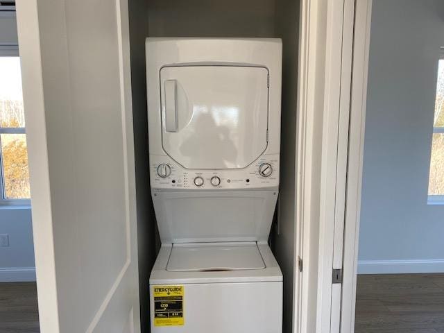 laundry area with stacked washer / drying machine and dark hardwood / wood-style floors