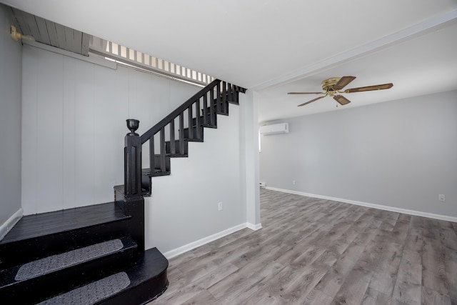 stairs with ceiling fan, wood-type flooring, and a wall mounted air conditioner