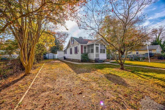 view of front facade with a sunroom, a shed, and a front yard