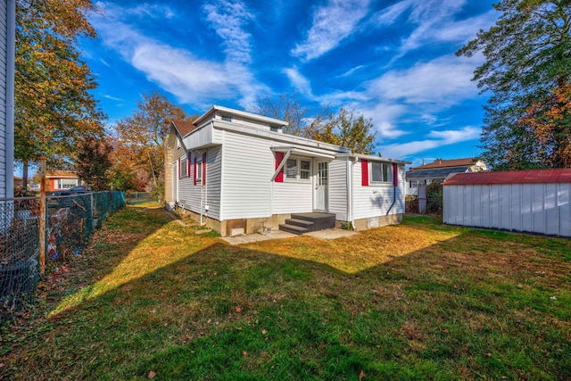 rear view of house featuring a storage unit and a lawn