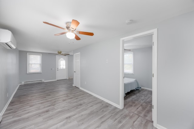 interior space featuring ceiling fan, an AC wall unit, baseboard heating, and light hardwood / wood-style flooring