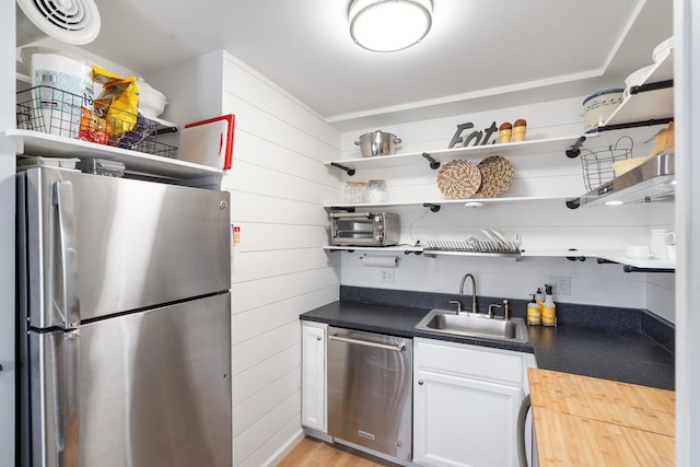 kitchen with wood counters, wood walls, white cabinets, sink, and appliances with stainless steel finishes