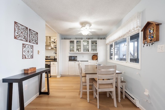 dining room featuring ceiling fan, light wood-type flooring, a textured ceiling, and a baseboard radiator