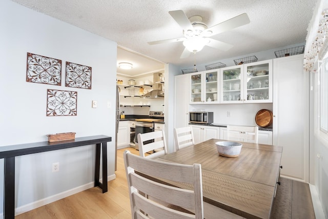 dining room featuring light wood-type flooring, a textured ceiling, and ceiling fan