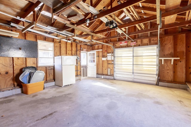 garage with a garage door opener and white refrigerator