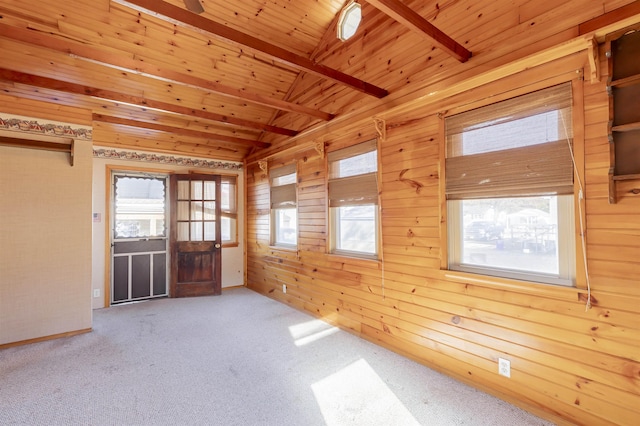 empty room with lofted ceiling with beams, wood walls, carpet floors, and wood ceiling