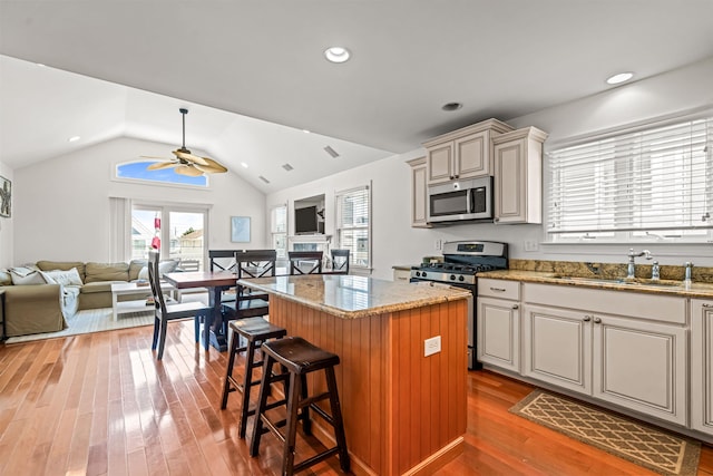 364 41st St E, Unit East, Avalon, NJ 08202 - kitchen featuring appliances with stainless steel finishes, a center island, light wood-style flooring, a ceiling fan, and light stone countertops