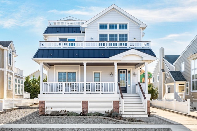 view of front of property featuring covered porch, a standing seam roof, metal roof, a balcony, and stairs