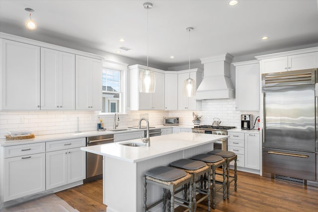 kitchen with premium range hood, appliances with stainless steel finishes, white cabinets, and pendant lighting