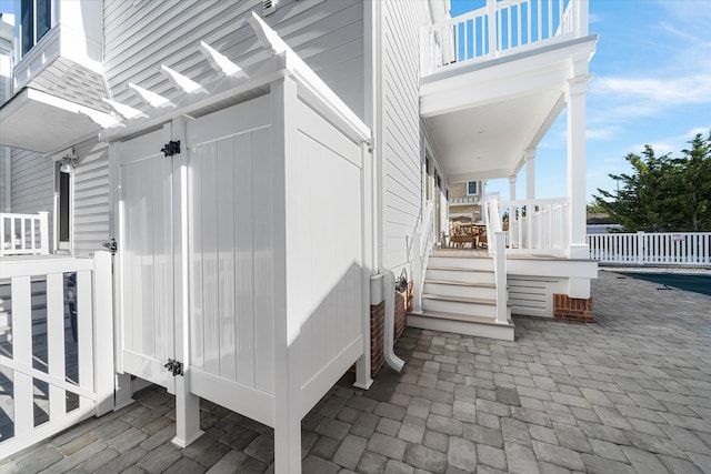 view of property exterior with a balcony, a shingled roof, and fence