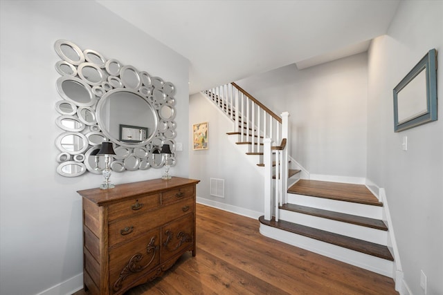 stairway featuring wood finished floors, visible vents, and baseboards