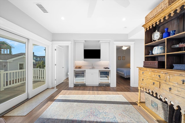 living area with recessed lighting, visible vents, ceiling fan, wood finished floors, and beverage cooler