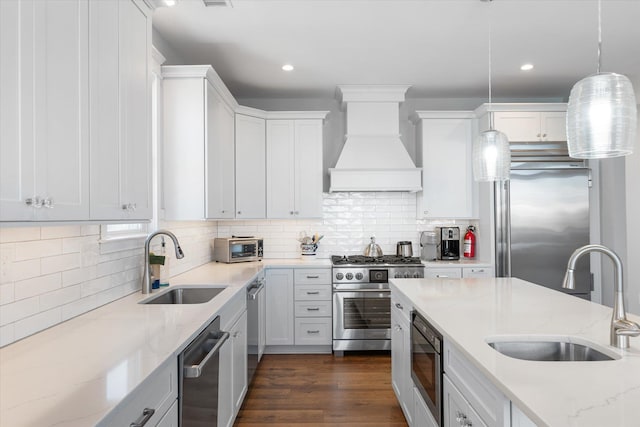 kitchen featuring hanging light fixtures, high end appliances, a sink, and custom range hood