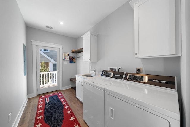 clothes washing area featuring cabinet space, visible vents, baseboards, wood finished floors, and washing machine and dryer