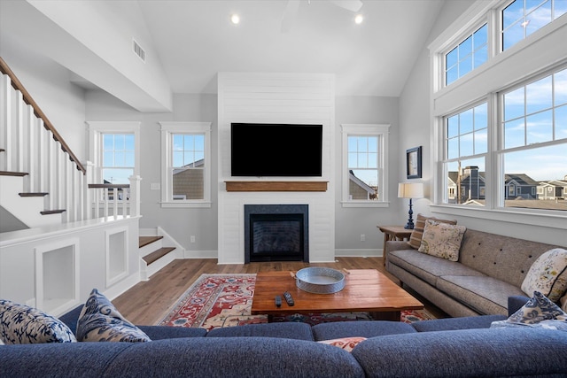 living area with a large fireplace, stairway, wood finished floors, and baseboards