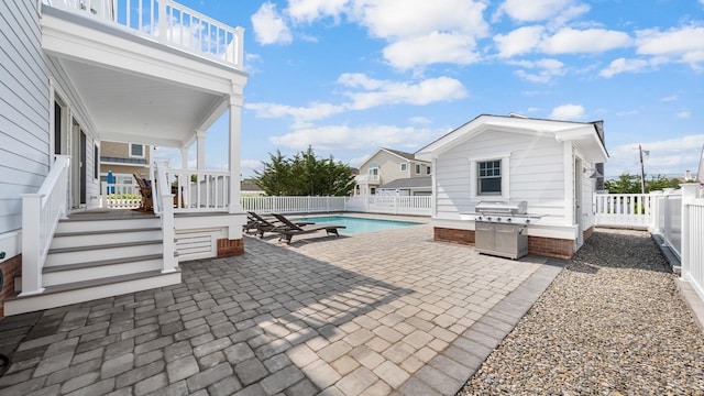 view of patio with a fenced in pool, a balcony, a fenced backyard, an outbuilding, and a grill