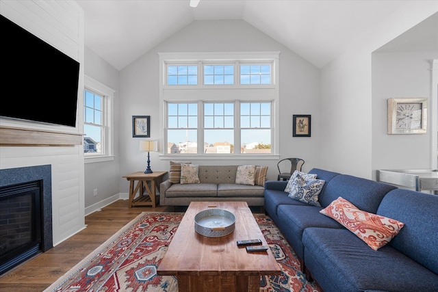 living room with lofted ceiling, a fireplace, baseboards, and wood finished floors