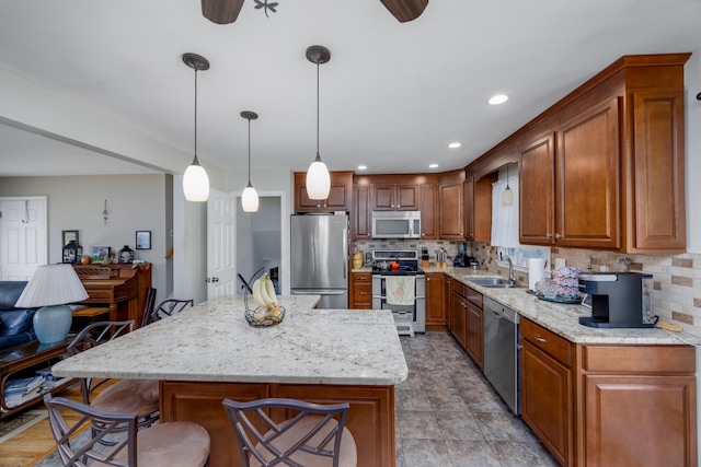 kitchen with appliances with stainless steel finishes, a kitchen island, pendant lighting, and light stone counters