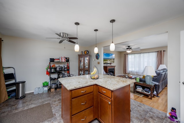 kitchen with decorative light fixtures, a center island, light stone countertops, and ceiling fan