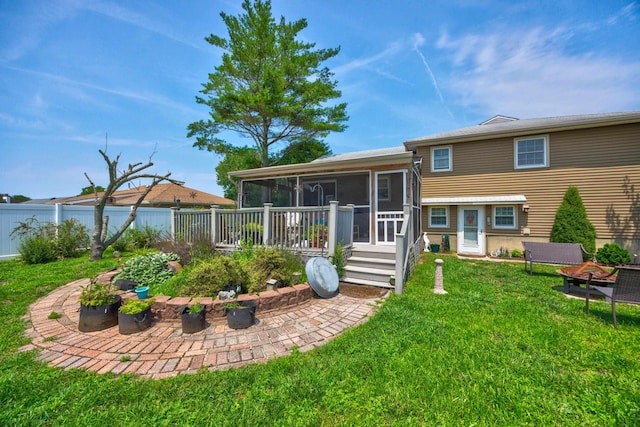 rear view of property featuring a sunroom, a yard, a fire pit, and a deck