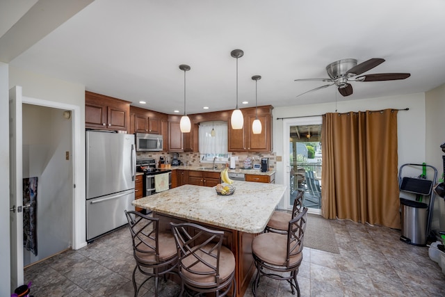 kitchen featuring ceiling fan, a center island, hanging light fixtures, stainless steel appliances, and decorative backsplash