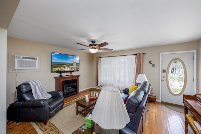 living room with ceiling fan, light wood-type flooring, and a wall mounted AC