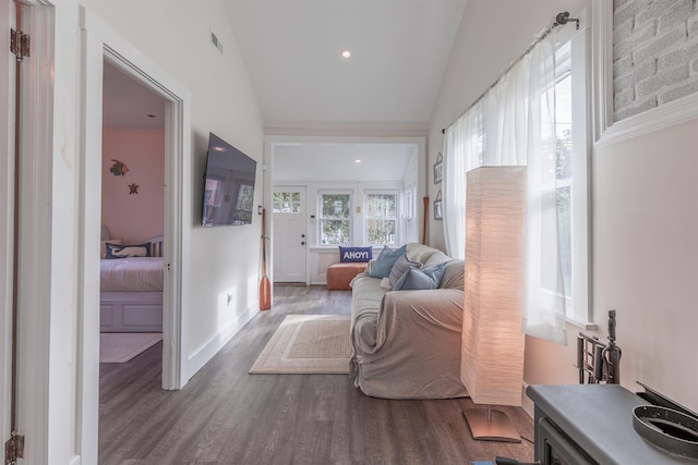 hall featuring wood finished floors, visible vents, baseboards, lofted ceiling, and recessed lighting