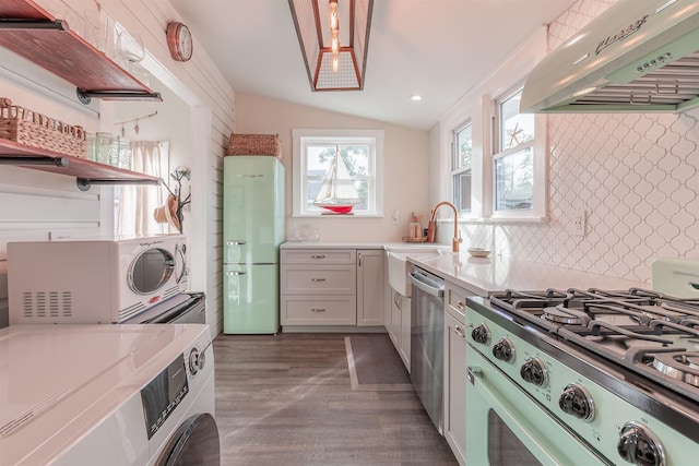 kitchen featuring freestanding refrigerator, gas stove, exhaust hood, lofted ceiling, and dishwasher