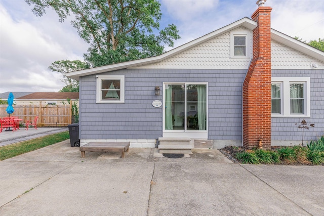 rear view of property with a patio, entry steps, a chimney, and fence